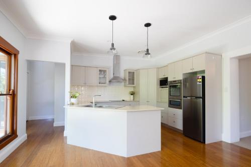 uma cozinha com armários brancos e um frigorífico preto em Kuzman Homestead em Mudgee
