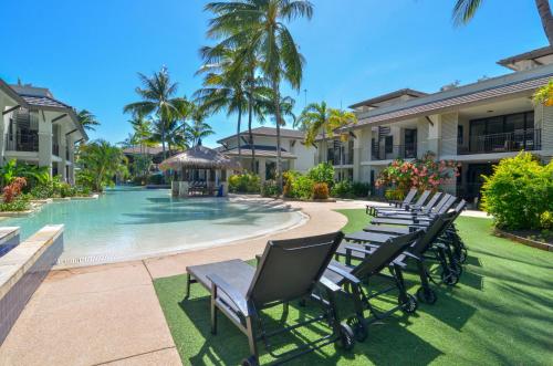 a group of chairs sitting next to a swimming pool at Seascape Holidays at Seascape Temple in Port Douglas