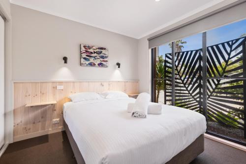 een slaapkamer met een groot bed en een groot raam bij The Anchorage Bermagui in Bermagui