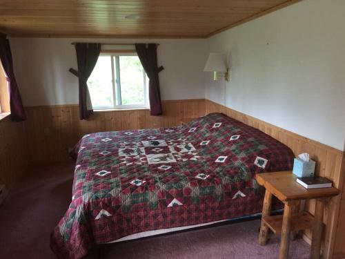 een slaapkamer met een bed met een dekbed en een tafel bij Denali Park Homestead in McKinley Park