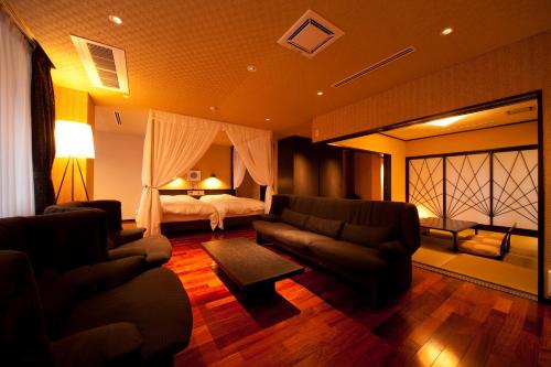 salon z łóżkiem, kanapą i krzesłami w obiekcie 由布院ユウベルホテル w mieście Yufu