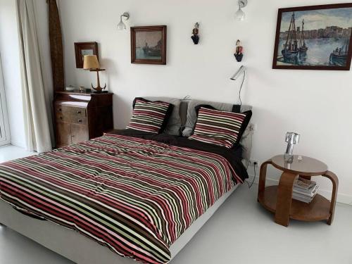 - une chambre avec un lit avec une couverture rayée et une table dans l'établissement Villa plain-pied, jardin, vélos et kayaks, à 370m de la plage à Landrellec. - FR-1-368-346, à Pleumeur-Bodou