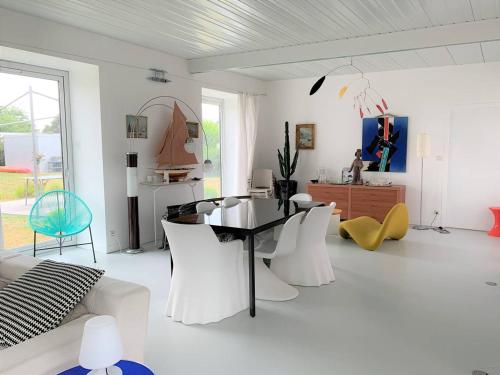 un salon blanc avec une table et des chaises dans l'établissement Villa plain-pied, jardin, vélos et kayaks, à 370m de la plage à Landrellec. - FR-1-368-346, à Pleumeur-Bodou