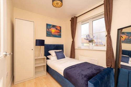 ein Schlafzimmer mit einem blauen Bett und einem Fenster in der Unterkunft Bristol's Coach House - 2 Bedroom Detached Apartment with Secure Parking in Bristol