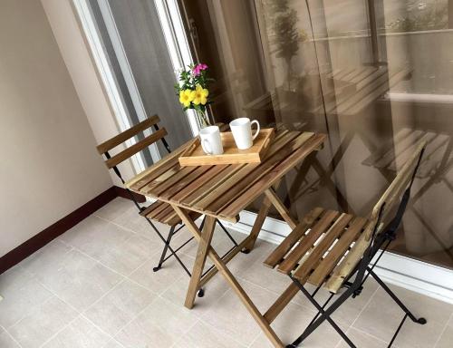 a wooden table with two chairs and flowers on it at Luxury Condo in Clark Pampanga beside Hilton Hotel and Casino in Angeles
