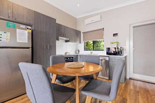 a kitchen with a wooden table and gray chairs at The Anchorage Bermagui in Bermagui