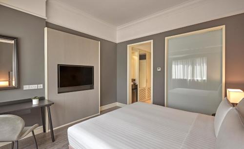 a bedroom with a bed and a desk and a television at Vibe Hotel Singapore Orchard in Singapore