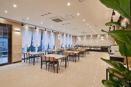 um restaurante com mesas e cadeiras e cortinas azuis em Hotel Hiveinn em Gwangju