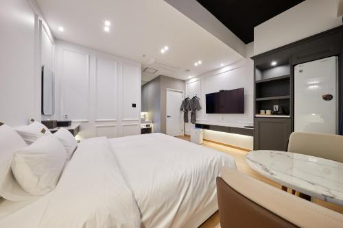 a white bedroom with a large bed and a table at Hotel Hiveinn in Gwangju