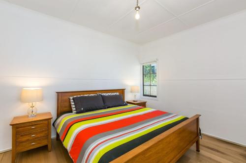 een slaapkamer met een bed met een kleurrijk gestreepte deken bij Grand Vue in Lorne