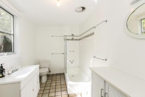 een witte badkamer met een bad, een toilet en een wastafel bij Grand Vue in Lorne