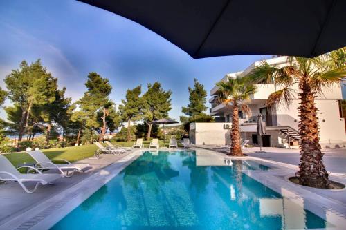 a swimming pool with chairs and palm trees at Pine Resort in Polychrono