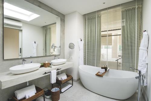 uma casa de banho com 2 lavatórios, uma banheira e um espelho. em Hu'u Villas em Seminyak