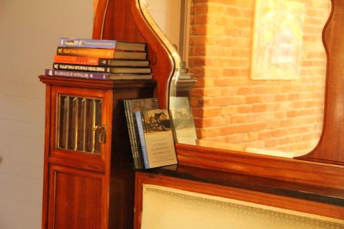 une pile de livres sur une étagère à côté d'un miroir dans l'établissement Villa Loebel 1881 Annex Building, à Juodkrantė