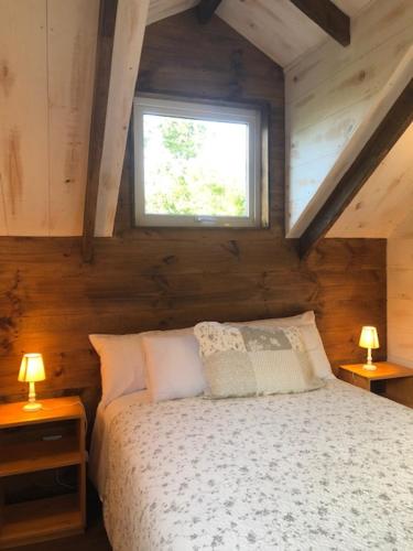 a bedroom with a bed with a window and two lamps at Stay Casa Hotel in Puerto Varas