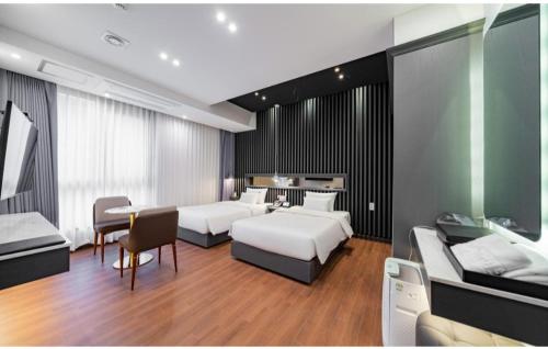 a hotel room with two beds and a dining table at Hotel Hiveinn in Gwangju