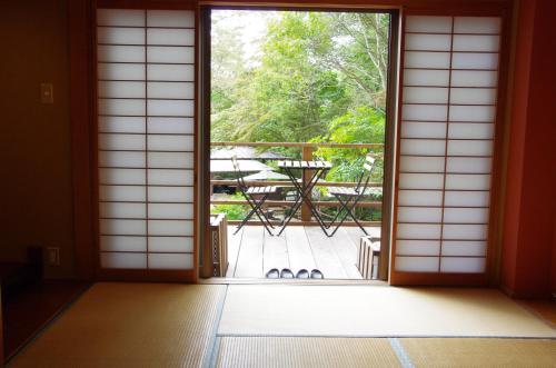 an open door to a patio with a table on a deck at Iwasu-so in Nakatsugawa