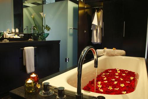a bathroom sink with a tub filled with red hearts at Sun Island Boutique Villas & Spa Seminyak in Seminyak