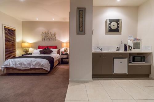 a bedroom with a bed and a kitchen with a microwave at Balconies Dolphincove in Tura Beach