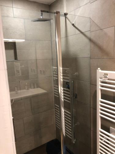 une douche avec une porte vitrée dans une salle de bain dans l'établissement Entre mer et commerces, à Wimereux