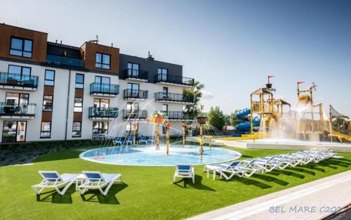 a pool with chairs and a water park in front of a building at Bel Mare Apartament E338 FREE PARKING in Międzyzdroje