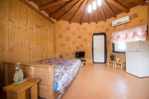 um quarto com uma cama e um frigorífico num quarto em Red Clay pension em Gangneung