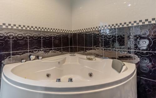 a white tub in a bathroom with black tiles at Peacock Pool Villa in Nong Prue