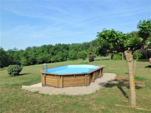 einen Pool inmitten eines Feldes mit einem Baum in der Unterkunft Cosy holiday home with swimming pool in Lavercantière