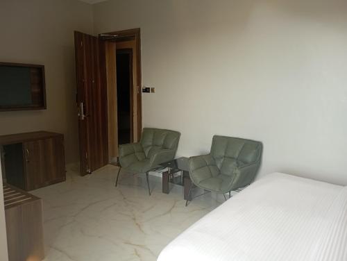 a bedroom with two chairs and a bed and a tv at Hotel Horizon Entebbe in Entebbe