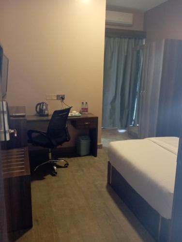 a bedroom with a bed and a desk and a chair at Hotel Horizon Entebbe in Entebbe