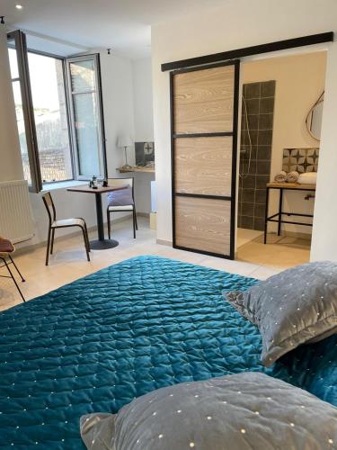 Un dormitorio con una gran cama azul y una mesa en La Secrète, en Vogüé