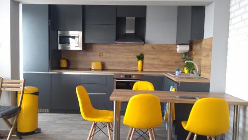 a kitchen with yellow chairs and a wooden table at Panorama apartment in Varna City