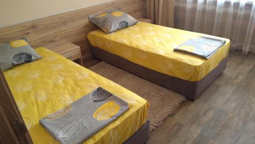 drie bedden in een kamer met gele lakens bij Panorama apartment in Varna