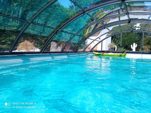 a swimming pool in a building with blue water at Mas des Vignes Piscine chauffée in Le Champ-Saint-Père