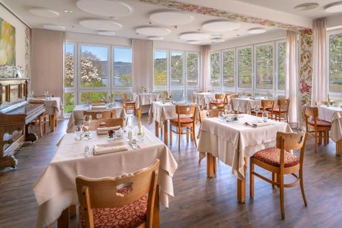 a restaurant with white tables and chairs and windows at Weinhotel Landsknecht in Sankt Goar