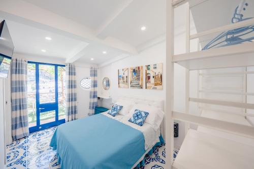 sypialnia z niebiesko-białym łóżkiem i oknem w obiekcie Villetta Actea w mieście Positano