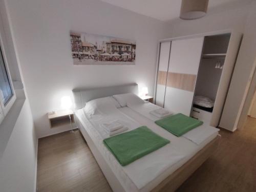 a bedroom with a white bed with two green pillows at Lovely one bedroom apartment in Ub