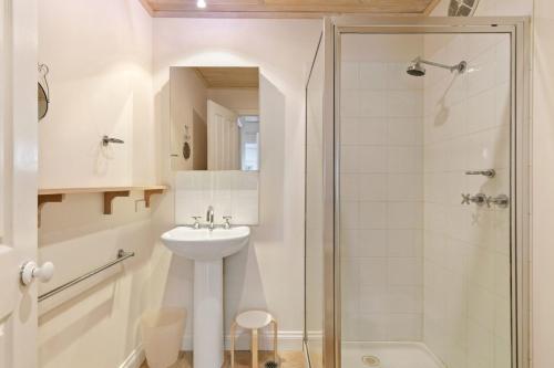 a white bathroom with a sink and a shower at Cora Lynn 13 in Lorne