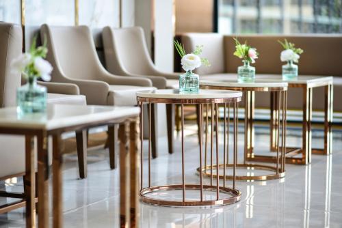 a row of tables with vases of flowers on them at Grand BS Airport Hotel Suvarnabhumi in Lat Krabang