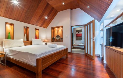 a bedroom with a large bed and a flat screen tv at Beachfront Kalim Beach Villa in Patong Beach
