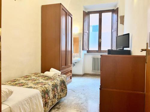 a bedroom with a bed and a dresser and a television at HostelCiompi in Siena
