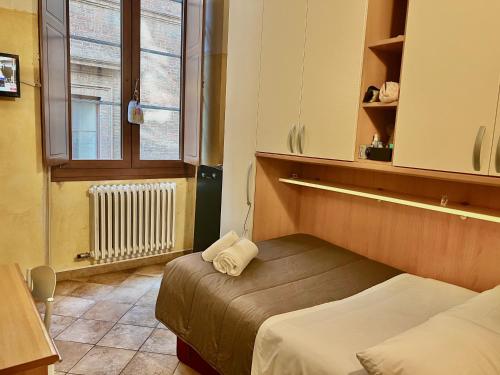 a small room with two beds and a window at HostelCiompi in Siena