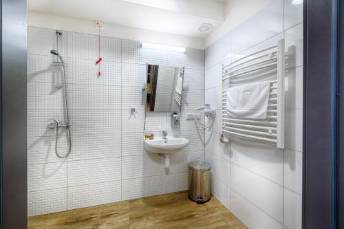 y baño blanco con lavabo y ducha. en Centrum Rehabilitacji Społecznej i Zawodowej ZAZ Słoneczne Wzgórze, en Tarnów