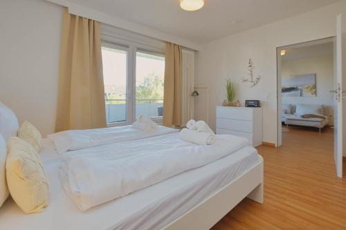 um quarto branco com uma cama grande e lençóis brancos em kutterbude Büsum - bude II em Büsum