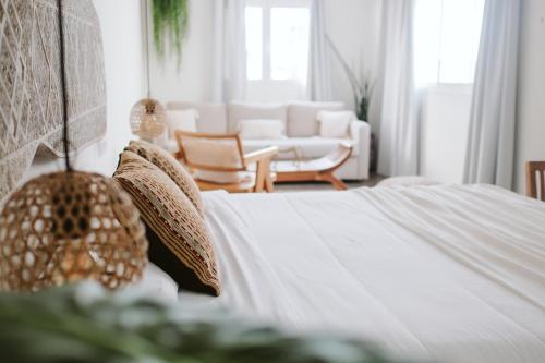 Habitación blanca con cama y sofá en Dreamsea Surf House Fuerteventura, en Corralejo