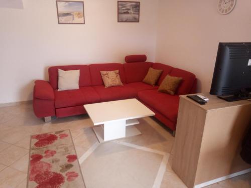 a living room with a red couch and a table at Apartmani Rab - Adrijana & Aleksandra in Banjol