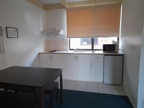 a small kitchen with a table and a microwave at Sundown Villas in Canberra