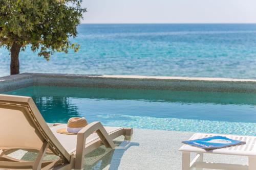 a straw hat sitting on a chair next to a swimming pool at Luxury Glamping Beach Villas Porto Bus in Bale