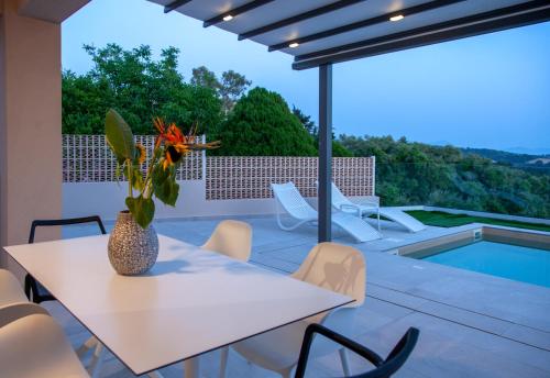 a patio with a table and chairs and a pool at LUMIERE VILLAS in Kanali