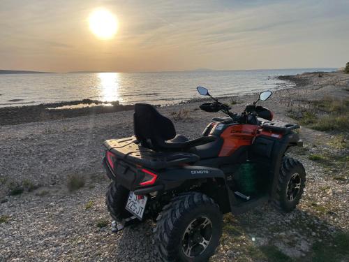 a quad bike parked on the beach with the sunset at Apartments Gemma in Mandre